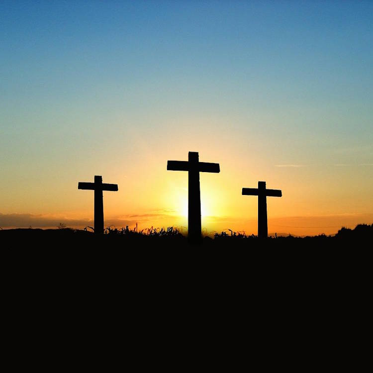 Three crosses on a hill at sunrise.