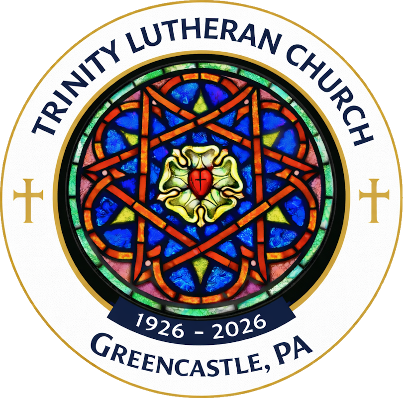 A circular 100th-anniversary logo for Trinity Lutheran Church in Greencastle, PA (1926–2026). The design features a white outer ring with navy blue text and two gold crosses flanking a central image. The center depicts a vibrant stained-glass window with intricate geometric patterns in blue, red, and gold. At the very heart of the window is the Luther Rose—a white flower containing a red heart with a small black cross.